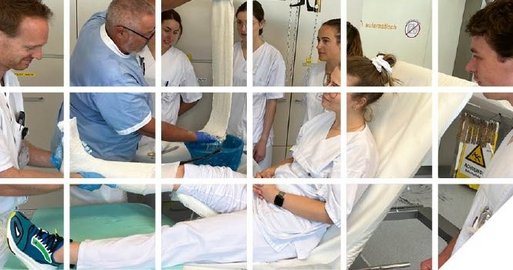 Studierende rund um ein Krankenbett auf dem eine Person mit Gips liegt