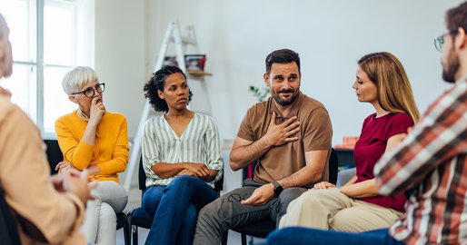 verschiedene Personen sitzen im Kreis und reden miteinander