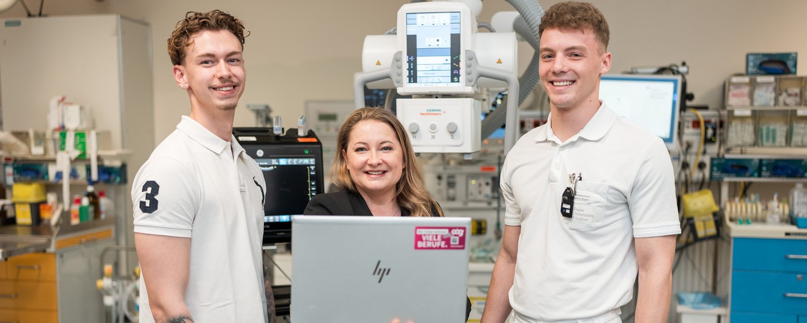 IT Mitarbeiterin mit Laptop in medizinischem Umfeld mit 2 Klinikmitarbeitern