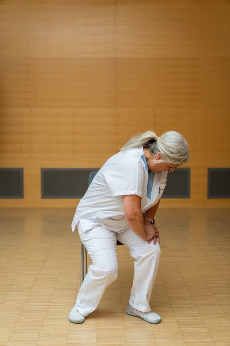 Füreder stützt sich beim seitlichen Aufstehen von Sessel auf ihr Knie ab