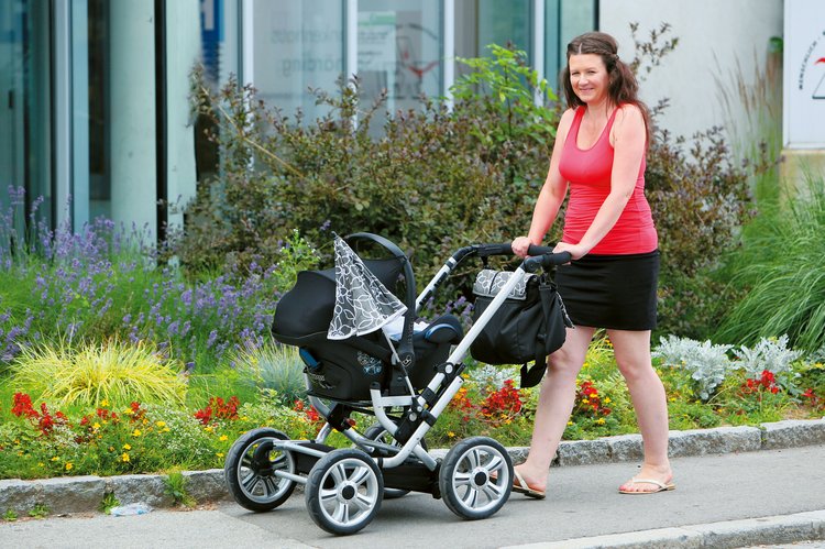 Mutter geht mit Baby im Kinderwagen spazieren