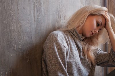 Frau hält sich depressiv den Kopf