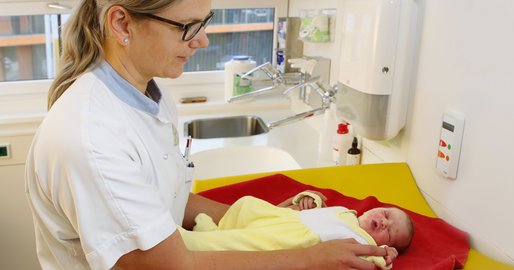 Zwei Mitarbeiterinnen mit einem Baby in der Hand