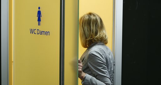 Person steht neben einer Toilettentür