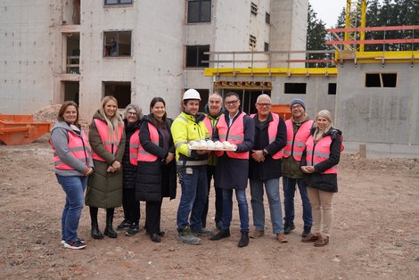 Direktor Mag. Franz Stadlmann übergibt mit einem Teil des Schulteams Krapfen an Polier Patrick Weißböck und seine Bauarbeiter.