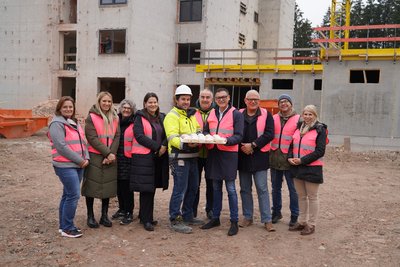 Direktor Mag. Franz Stadlmann übergibt mit einem Teil des Schulteams Krapfen an Polier Patrick Weißböck und seine Bauarbeiter.