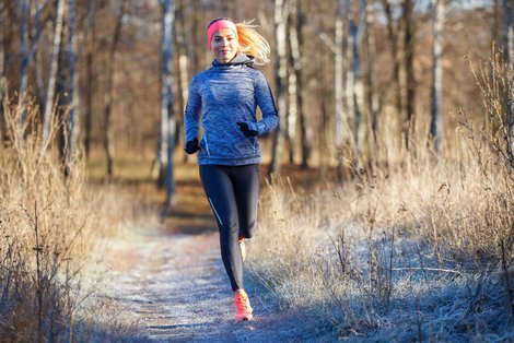 Läuferin joggt im Winter durch Wald