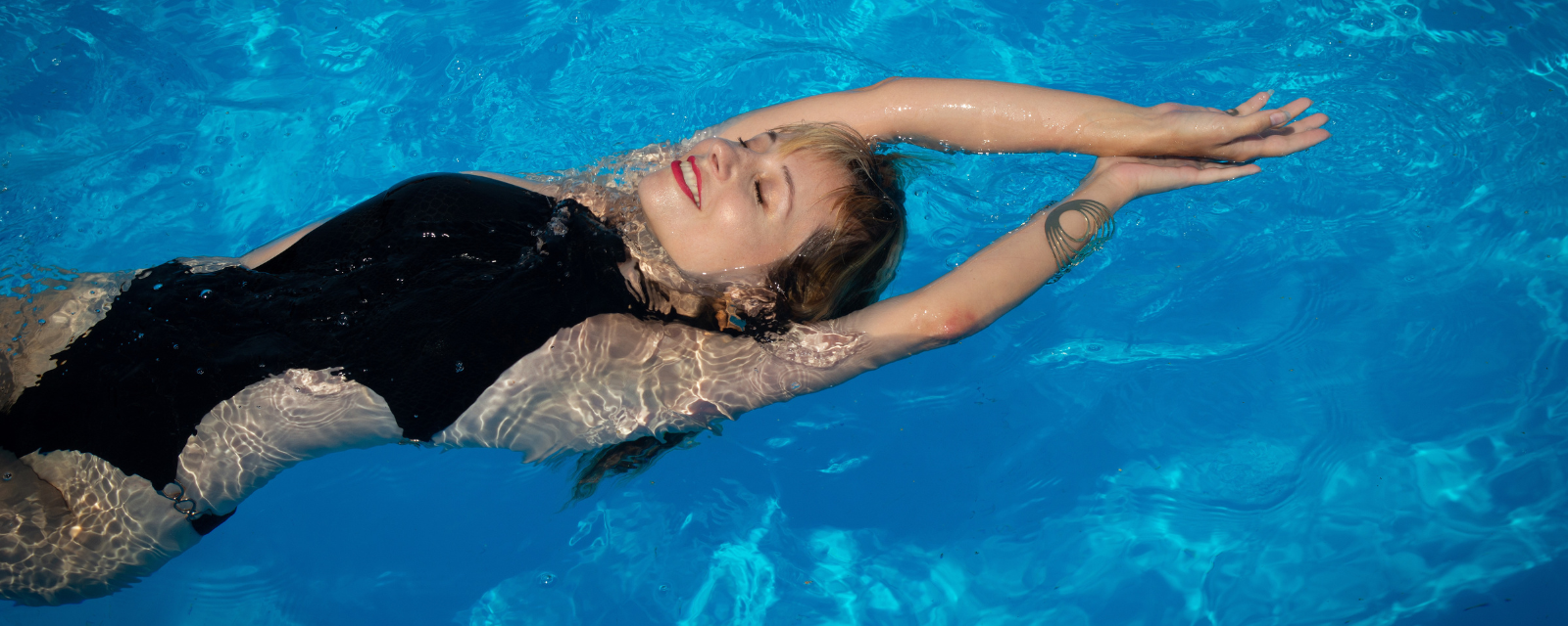 Frau in Badeanzug schwimmt am Rücken in einem Pool