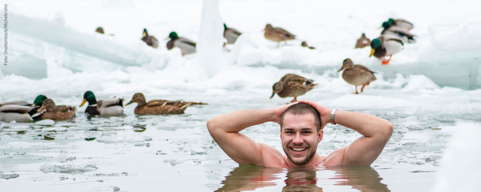 Mann beim Eisbaden mit Enten im Hintergrund