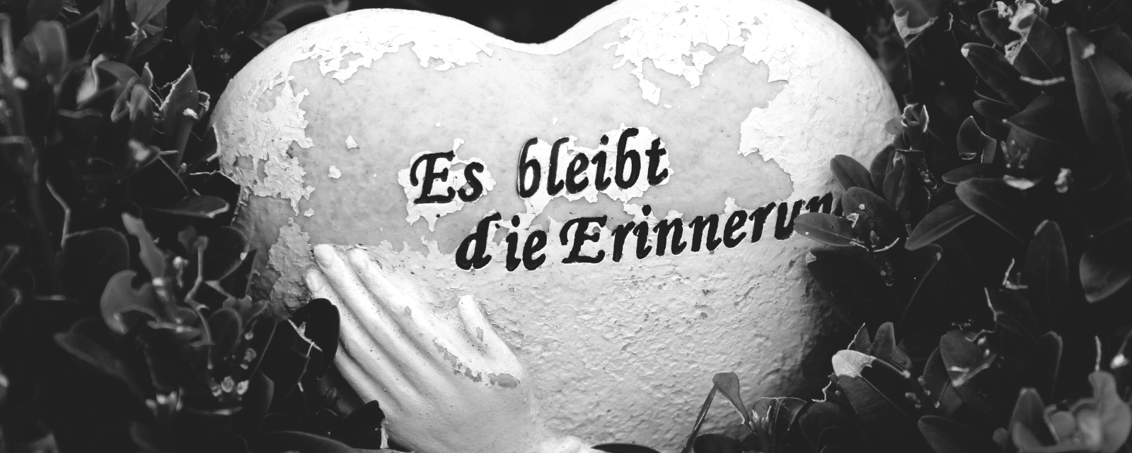 Stein in Herzform mit Text "Es bleibt die Erinnerung".